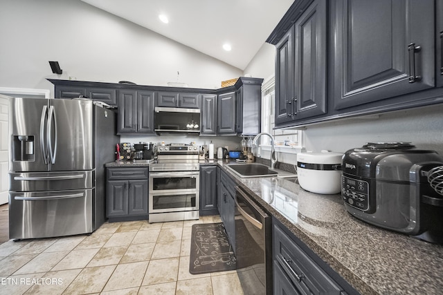 kitchen with appliances with stainless steel finishes, a sink, high vaulted ceiling, dark stone counters, and light tile patterned floors