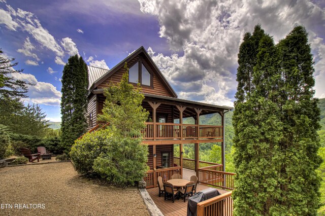 1551 Mountain Dreams Way, Sevierville, TN 37862 - rear view of house featuring a wooden deck, outdoor dining space, metal roof, and log veneer siding