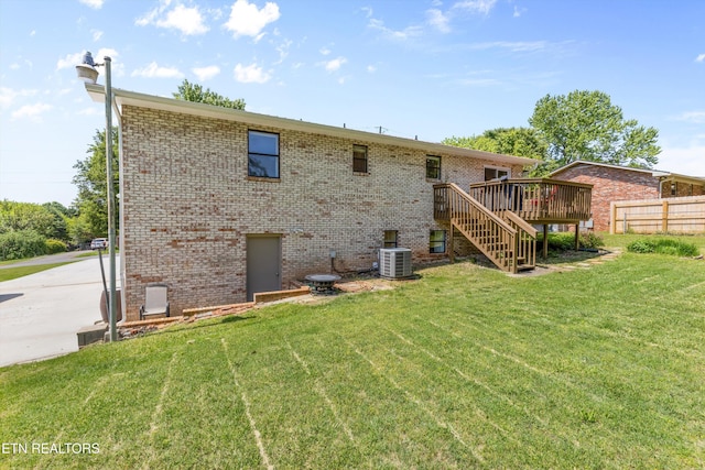 back of house featuring a lawn, a deck, central air condition unit, brick siding, and stairs
