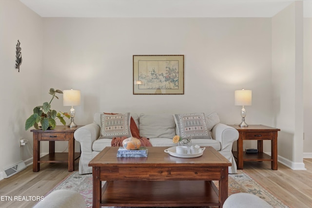 living area featuring baseboards, light wood-style flooring, and visible vents