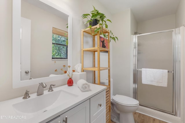 full bathroom with wood finished floors, a stall shower, toilet, and vanity