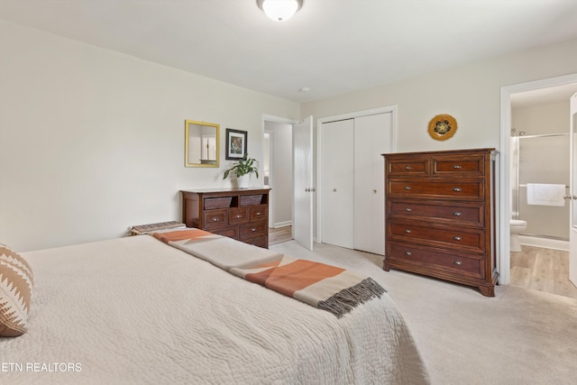 bedroom with baseboards, a closet, connected bathroom, and light colored carpet