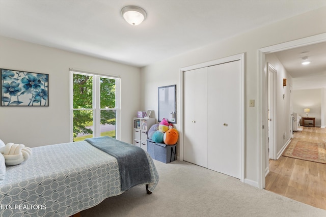 bedroom featuring baseboards, light colored carpet, and a closet
