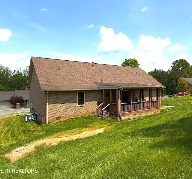 back of property with brick siding, roof with shingles, and a lawn