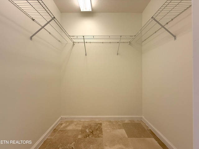 spacious closet featuring stone finish floor