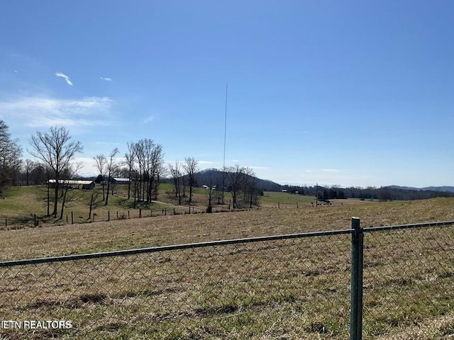 view of jungle gym featuring fence and a rural view