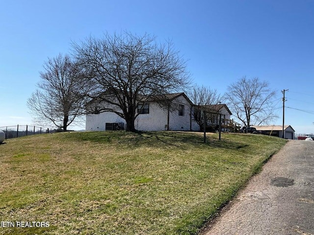 view of side of home with fence and a yard