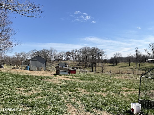 view of yard featuring an outdoor structure, fence, and a rural view