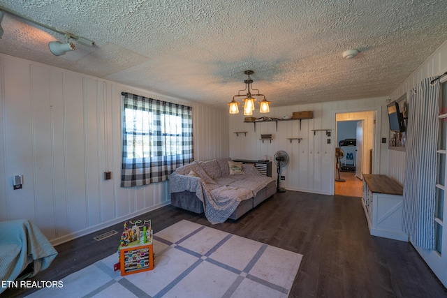 bedroom with a textured ceiling, dark wood finished floors, and an inviting chandelier