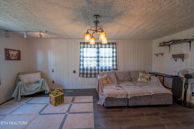living area with baseboards, a textured ceiling, wood finished floors, and a chandelier