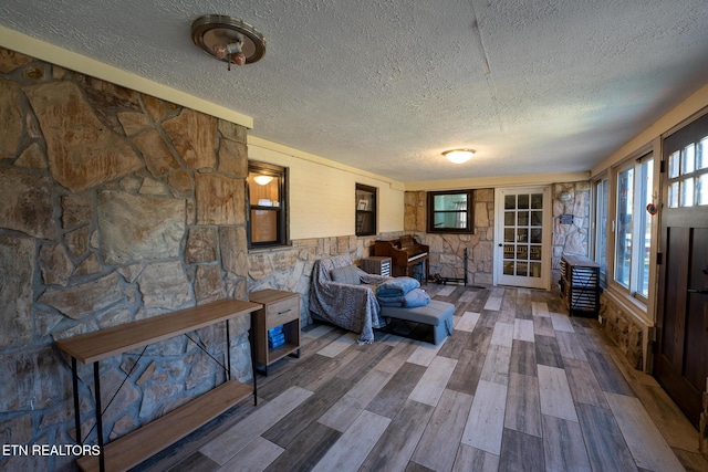 living area featuring french doors, a textured ceiling, and wood finished floors