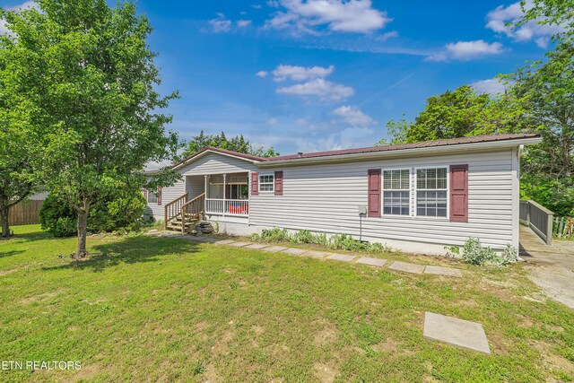 manufactured / mobile home featuring a front lawn, covered porch, and metal roof
