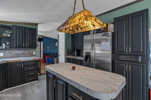 kitchen with open shelves, stainless steel refrigerator with ice dispenser, light countertops, dark cabinets, and light wood-style flooring