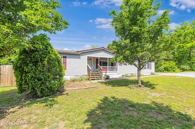 manufactured / mobile home featuring a porch, a front lawn, and fence