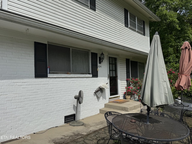 entrance to property featuring a patio area and brick siding
