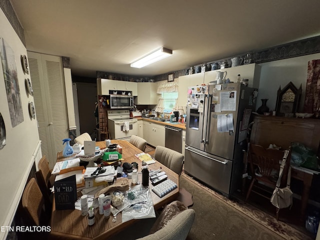 kitchen with carpet floors, white cabinets, and stainless steel appliances