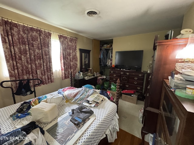 bedroom featuring a closet, wood finished floors, and visible vents