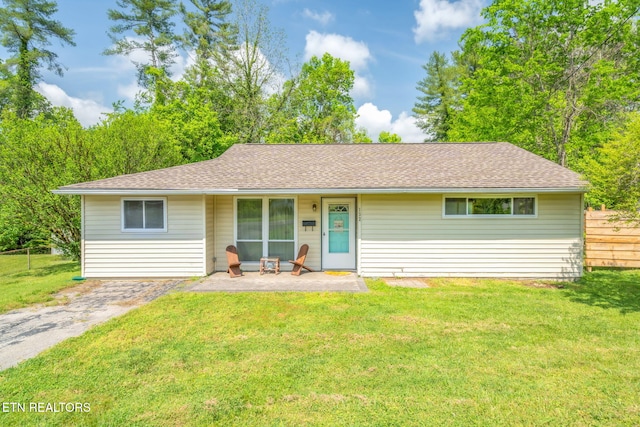 ranch-style home featuring a shingled roof, a front lawn, and fence