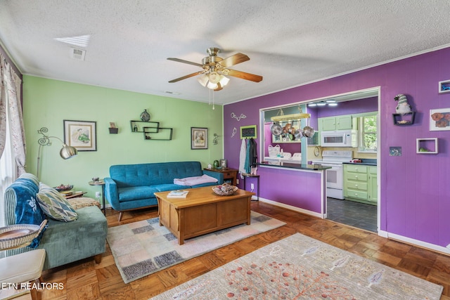 living room featuring a textured ceiling, visible vents, baseboards, and ceiling fan