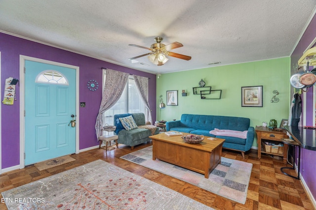 living room featuring ceiling fan, a textured ceiling, visible vents, and ornamental molding