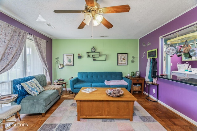 living room featuring a textured ceiling, visible vents, baseboards, and ceiling fan