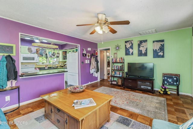 living area with crown molding, visible vents, baseboards, and a ceiling fan