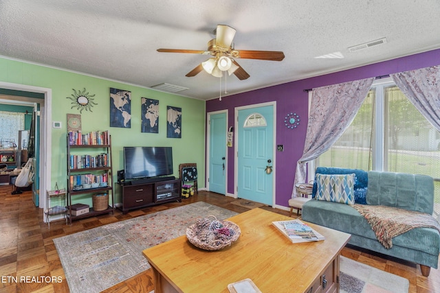 living room with a textured ceiling, a ceiling fan, and visible vents