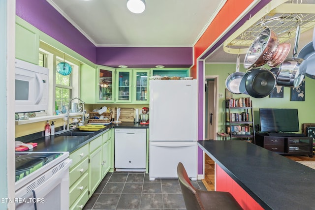 kitchen with a sink, white appliances, crown molding, glass insert cabinets, and dark countertops