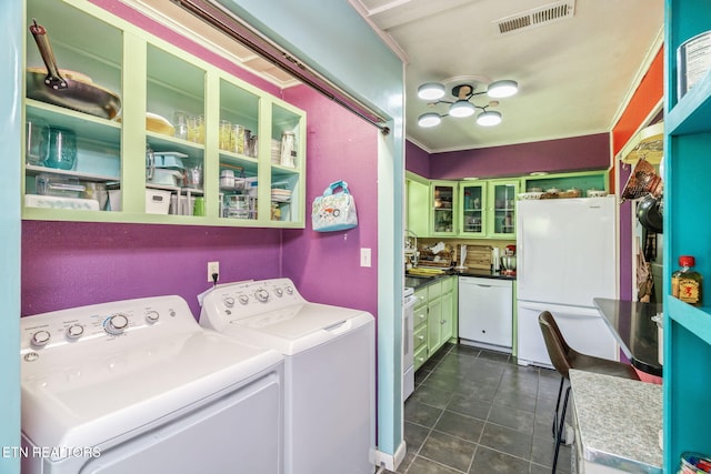 washroom with washing machine and dryer, dark tile patterned floors, visible vents, and crown molding