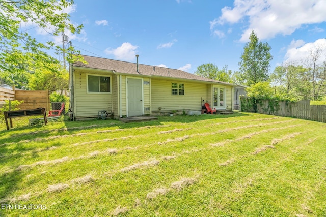back of house featuring a fenced backyard and a lawn
