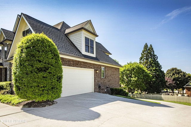 719 Lake Vista Ln Unit 3, Knoxville, TN 37934 - view of property exterior featuring fence, a shingled roof, brick siding, a garage, and concrete driveway