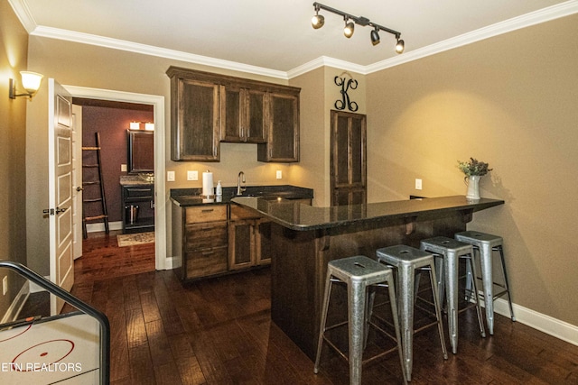 719 Lake Vista Ln Unit 3, Knoxville, TN 37934 - kitchen featuring dark wood-style flooring, dark brown cabinets, a peninsula, baseboards, and a kitchen bar