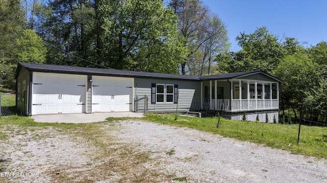 view of front of property featuring covered porch, fence, an attached garage, and driveway