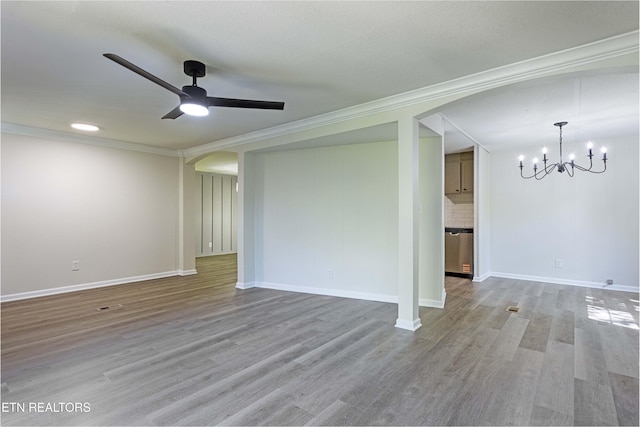 unfurnished living room with crown molding, arched walkways, ceiling fan with notable chandelier, and wood finished floors