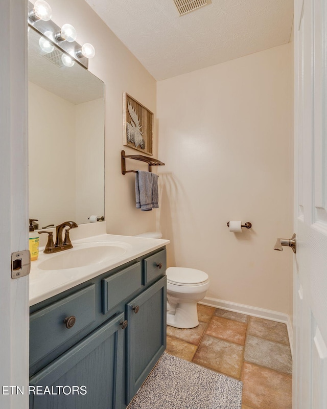 half bathroom with toilet, visible vents, baseboards, and vanity