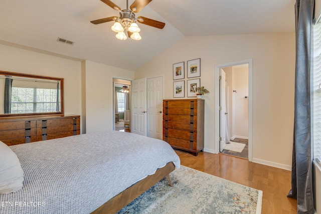 bedroom featuring light wood finished floors, multiple windows, visible vents, and lofted ceiling