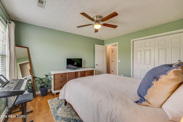 bedroom featuring a ceiling fan, a closet, baseboards, visible vents, and light wood-style floors