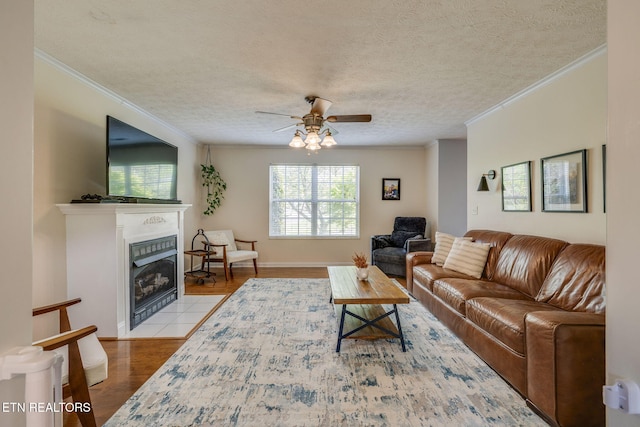 living room featuring a tile fireplace, wood finished floors, a ceiling fan, and ornamental molding