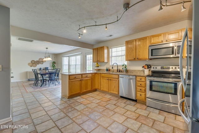 kitchen with a peninsula, a sink, visible vents, light stone countertops, and appliances with stainless steel finishes