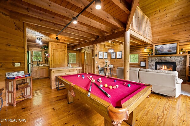 playroom with rail lighting, light wood finished floors, and wooden walls