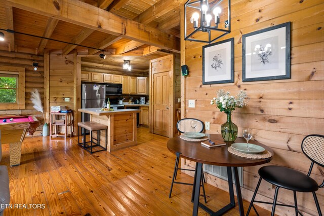 dining area with wood walls, light wood finished floors, wooden ceiling, and beamed ceiling