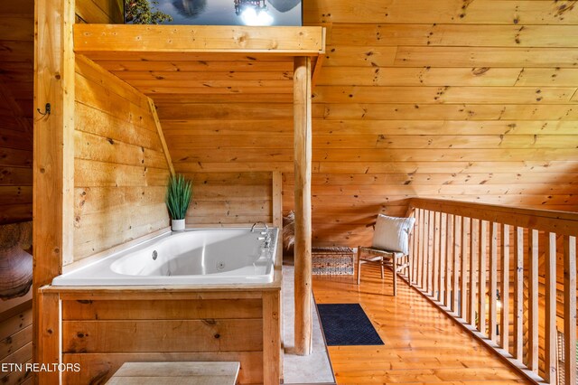 full bathroom with wood finished floors, lofted ceiling, and a jetted tub
