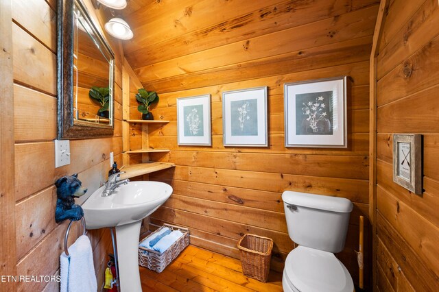 bathroom with wood walls, toilet, and hardwood / wood-style floors