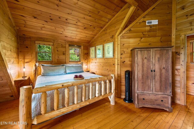 bedroom featuring visible vents, wood walls, lofted ceiling, light wood-type flooring, and wooden ceiling