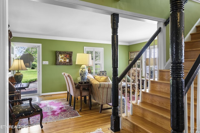 interior space with baseboards, ornamental molding, and wood finished floors