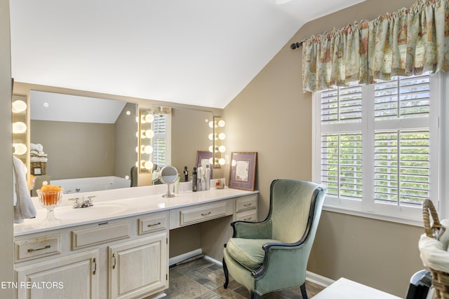 full bath featuring baseboards, lofted ceiling, a tub, and vanity