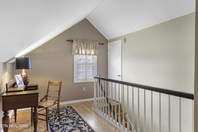 office area featuring baseboards, vaulted ceiling, and wood finished floors