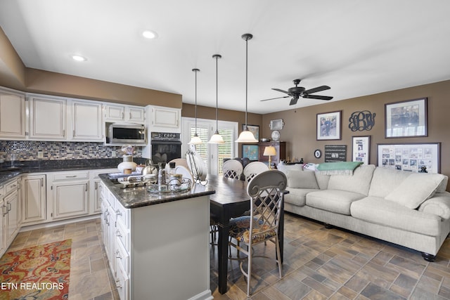 kitchen featuring a kitchen island, a ceiling fan, stainless steel microwave, open floor plan, and oven