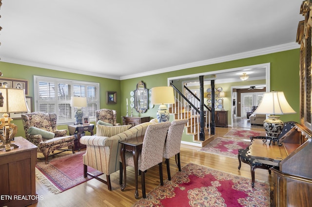 living area with stairway, ornamental molding, and wood finished floors