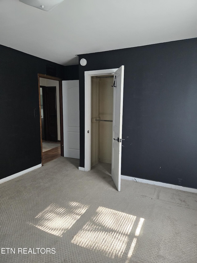 unfurnished bedroom with carpet floors, baseboards, and a closet